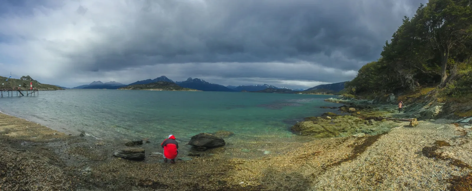 Visitor on the stony shore of the Beagle Channel under storm clouds