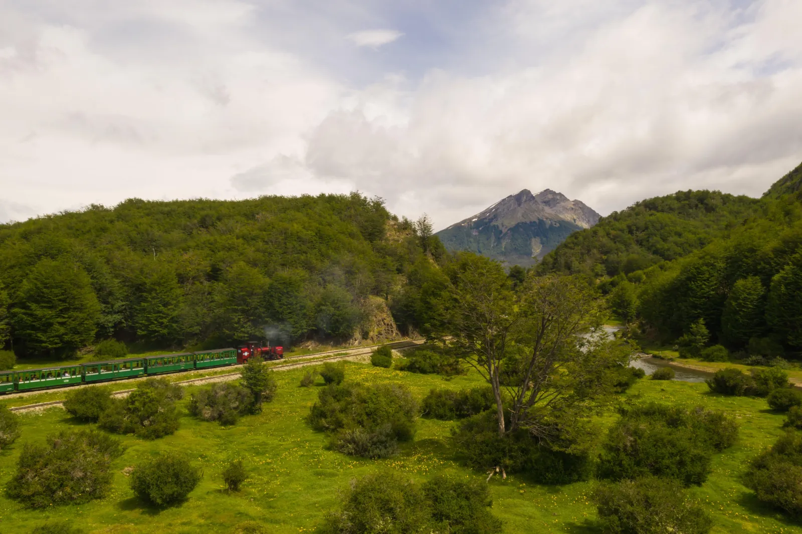 Green carriages crossing an open valley below a peak in the national park