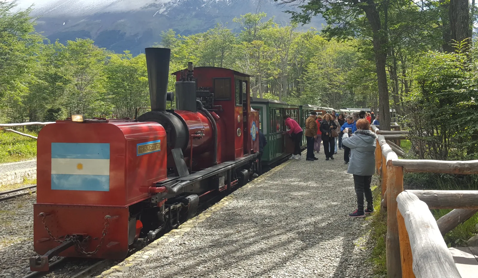 Passengers beside a red steam locomotive at the station